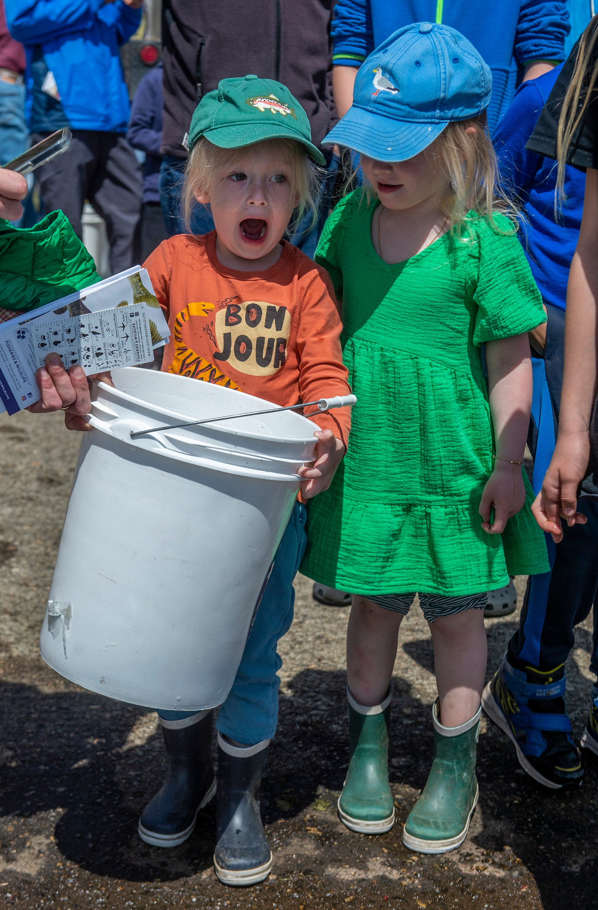 Mitchell Moore, 3, left, of Southborough, and his sister, Gray, 4, prepare to release a bucket of brown trout into the Hopkinton Reservoir, April 17, 2024.